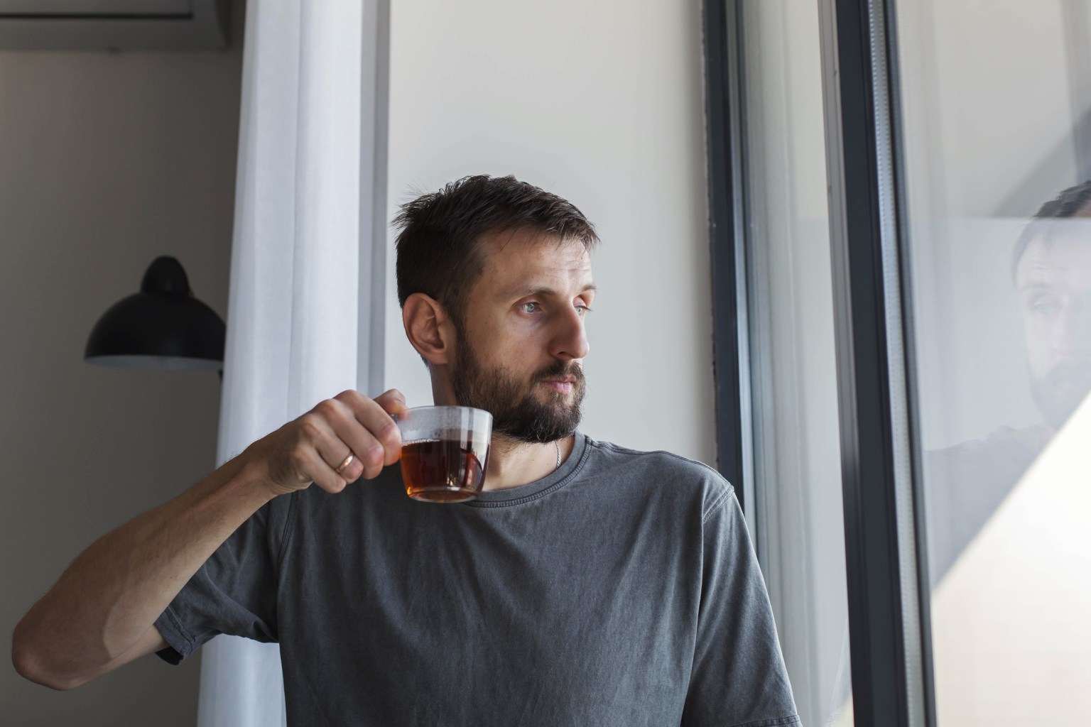 A man drinking tea by the window in calm morning light