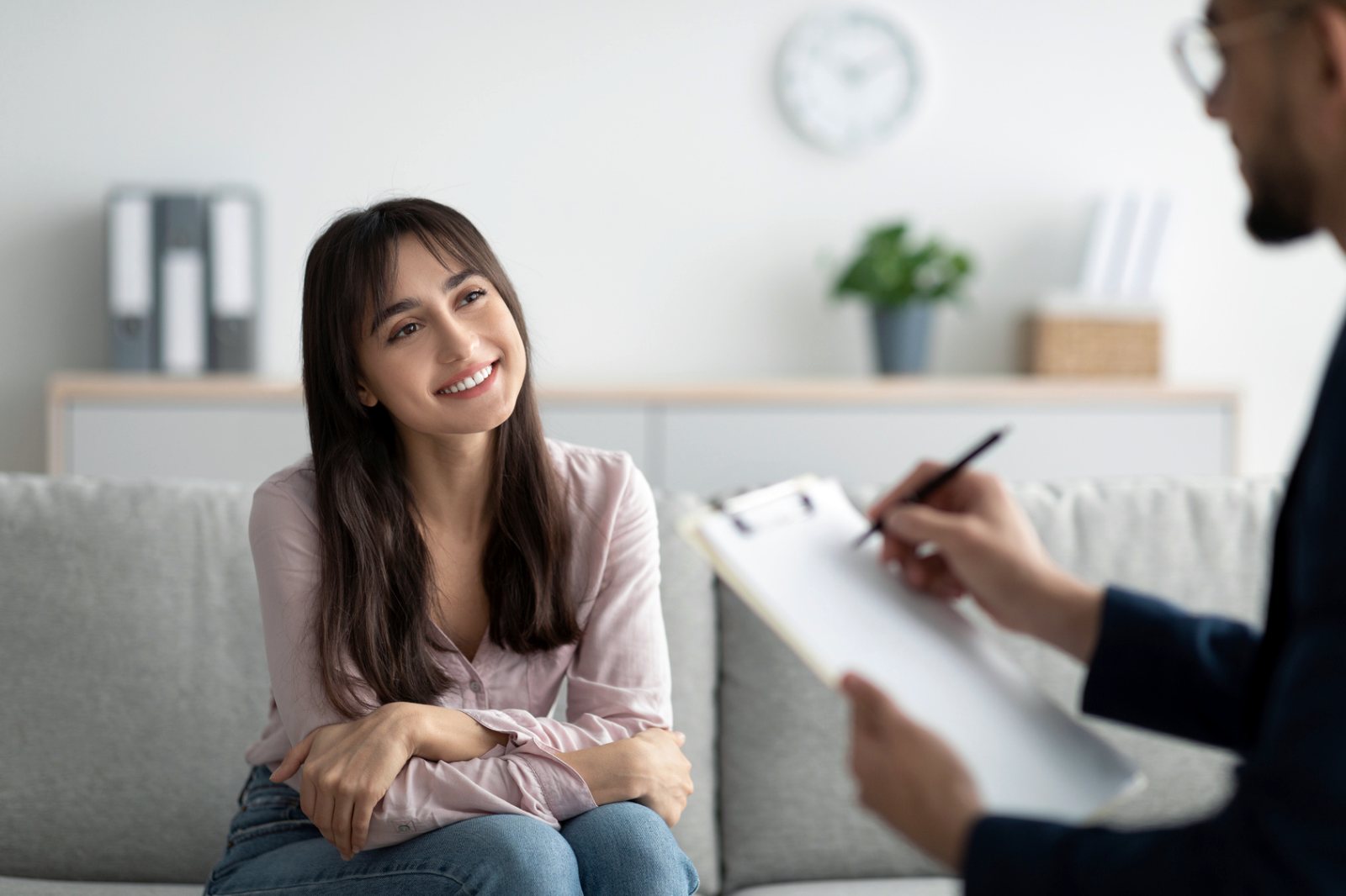 A young woman smiling during a conversation on a sofa in a bright office