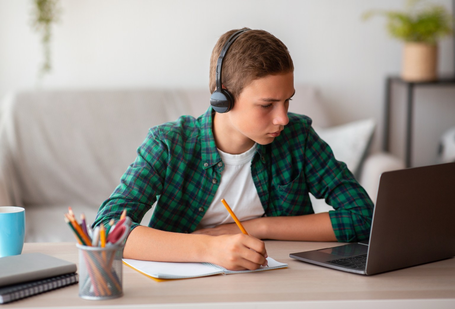 A focused student with headphones studying at home