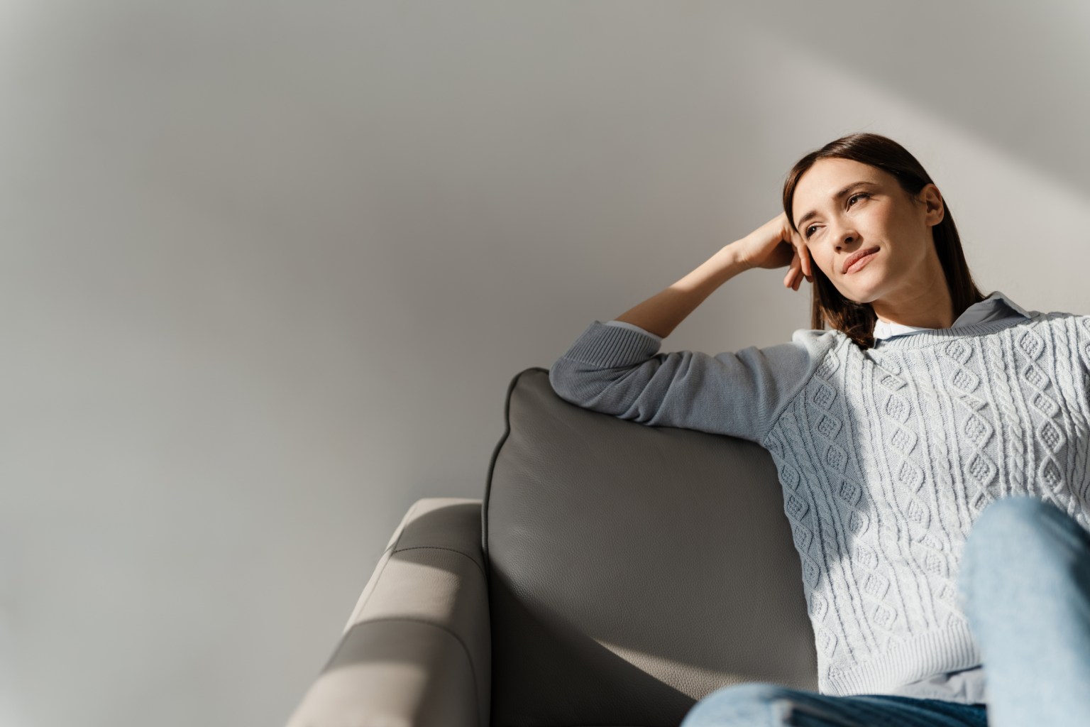 A woman relaxing on a sofa in a bright, calm living room